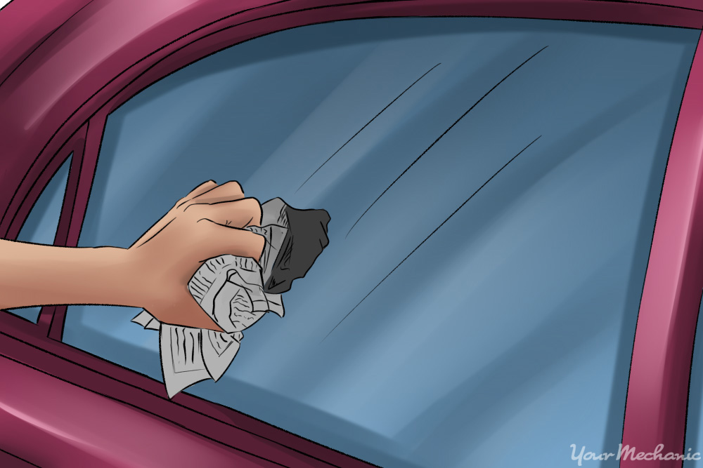 3x-how-to-clean-your-car-with-home-ingredients-peson-wiping-down-the-window-with-a-newspaper