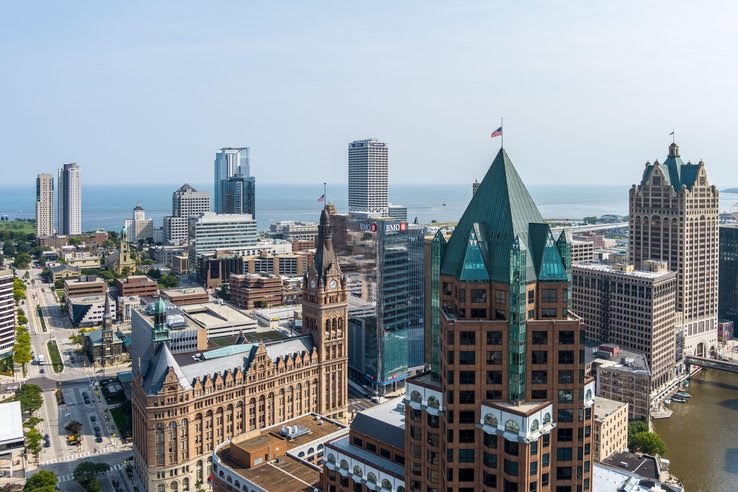 An aerial image of downtown Milwaukee featuring skyscrapers riverwalk