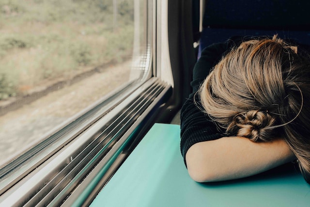 Woman resting with her head down on a train seat, appearing to be taking a moment of relaxation during the journey.