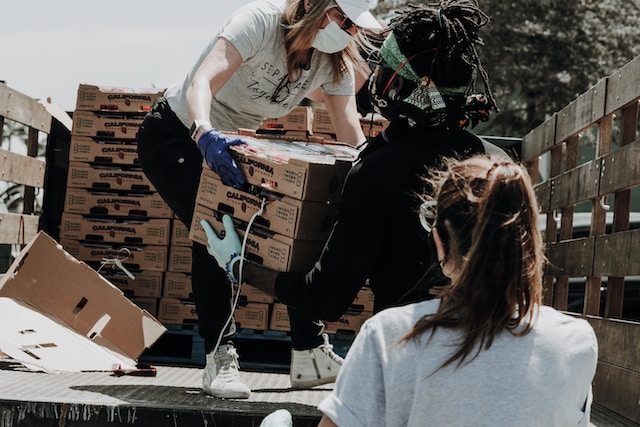 Group of volunteers transferring boxes of fresh berries from a truck to donate to a charity organization, contributing to a community's well-being.
