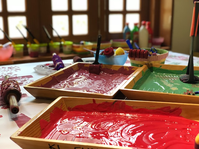 A home daycare table with various paints and brushes.