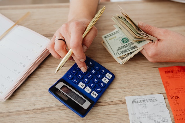 A woman is using a calculator to add up money and receipts for frugal living.
