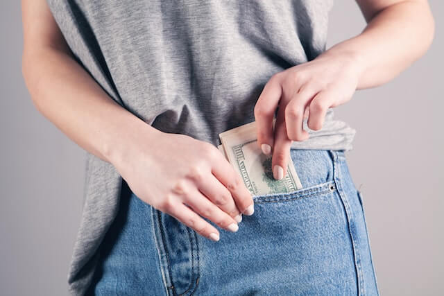 A frugal person putting money in their pocket. 