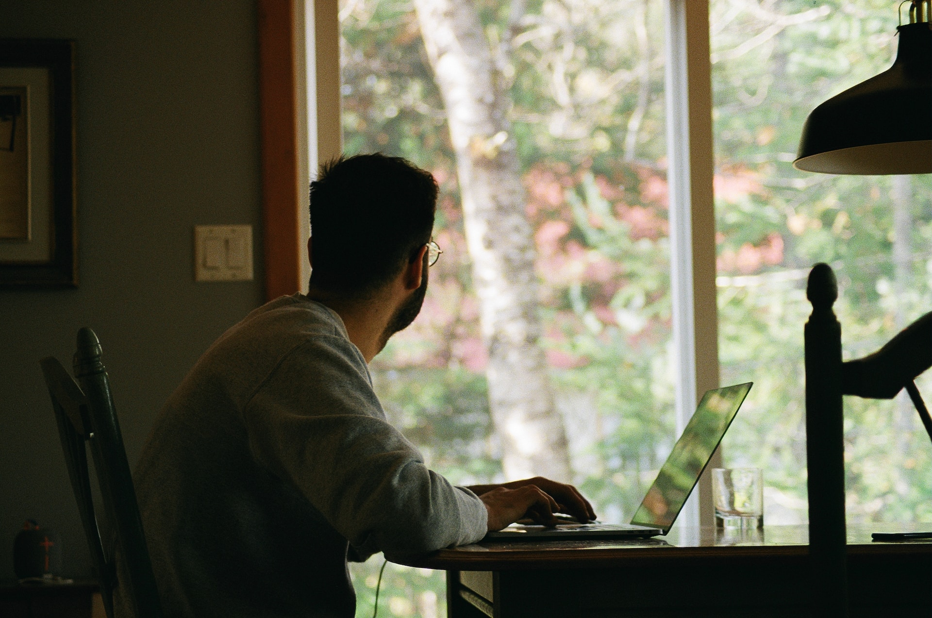 man with a laptop looking out of the window.