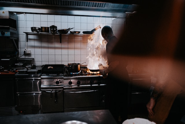 Man in a kitchen frying food on the stove.