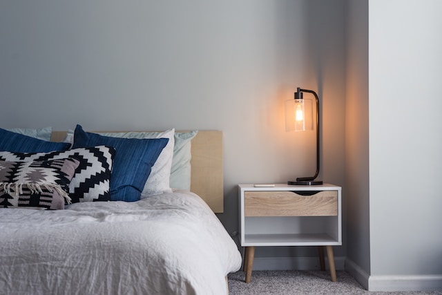 A bed and a nightstand with a lamp in a cozy sleeping space.