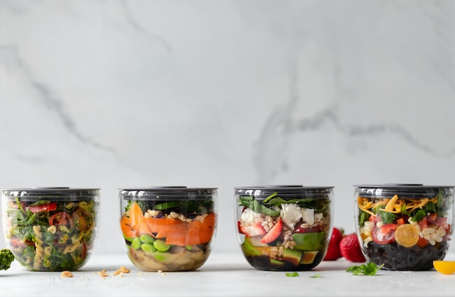 four meal prep containers with salads